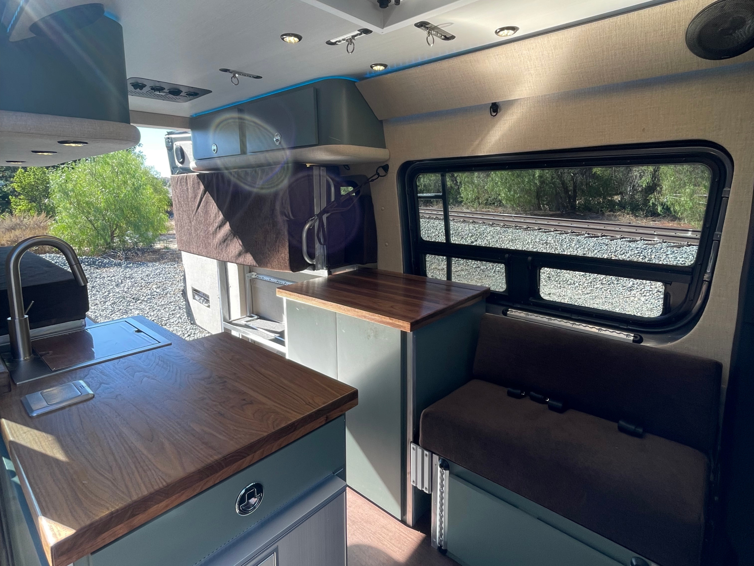 the interior of a campervan with a fridge, half shower, and pull down bed in the back