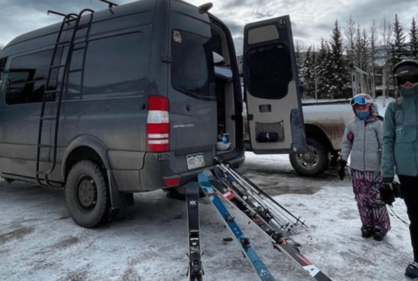 two people next to their campervan with skis in the snow