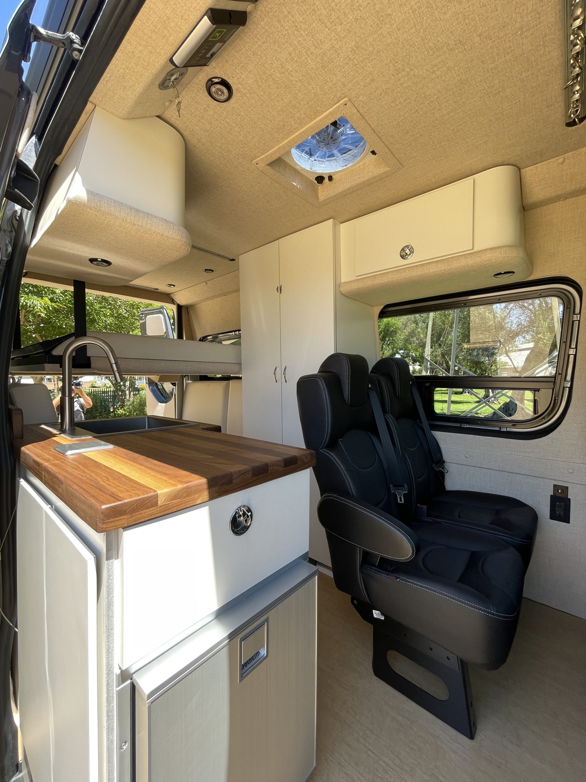 a sprinter campervan with a shower, kitchen, and drop down electric bed