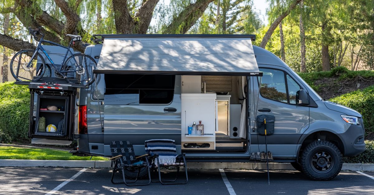 a campervan with two chairs, hiking poles, and a mountain bike on the back.