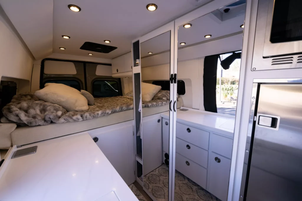 the inside of a campervan with a platform bed and large bathroom and mirror